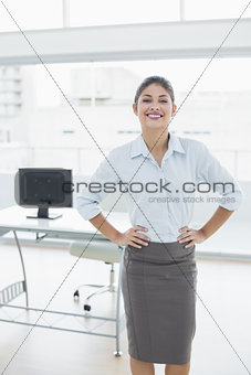 Elegant businesswoman with hands on hips in office