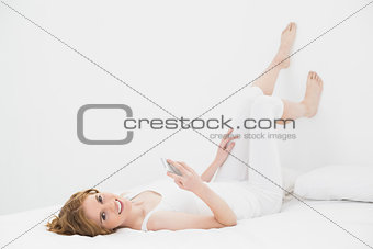 Portrait of relaxed woman with mobile phone in bed