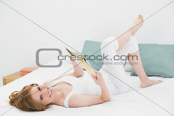 Portrait of relaxed woman reading a book in bed