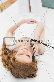 Relaxed woman using telephone in bed