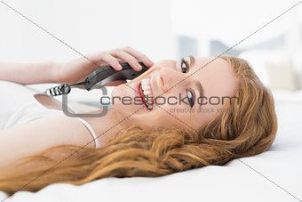 Relaxed young woman using telephone in bed