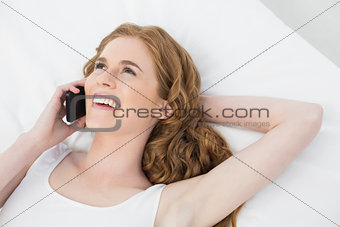 Cheerful woman using mobile phone in bed