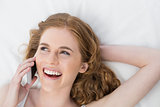 Cheerful woman using mobile phone in bed