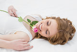 Pretty relaxed woman resting in bed with rose