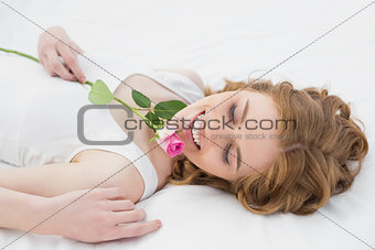 Pretty relaxed woman resting in bed with rose