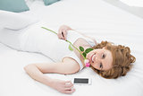 Pretty young woman resting in bed with rose
