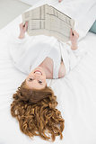 Pretty young blond reading newspaper in bed