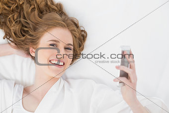 Relaxed young blond with mobile phone in bed