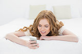 Relaxed blond looking at mobile phone in bed