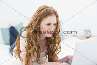 Casual young blond using laptop in bed