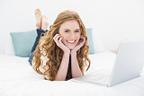 Portrait of smiling casual blond using laptop in bed