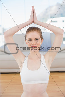 Woman with joined hands over head at fitness studio