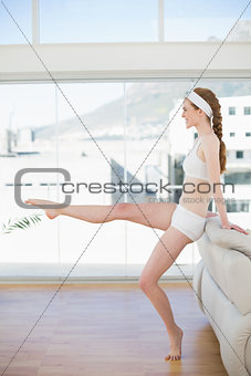 Toned woman stretching leg in fitness center