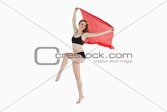 Full length of a sporty woman holding red fabric