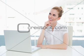 Thoughtful businesswoman using laptop at office desk