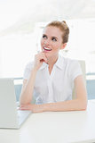 Businesswoman looking up while using laptop at office