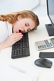 Asleep businesswoman yawning on keyboard at office