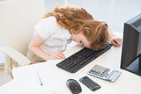 Businesswoman resting head on keyboard at office