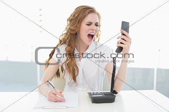 Businesswoman shouting into the phone at office