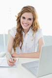 Smiling elegant businesswoman writing document at desk