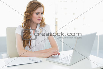 Serious businesswoman using laptop at office