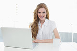 Smiling businesswoman using laptop at office