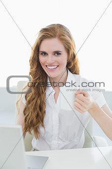 Smiling businesswoman drinking coffee using laptop