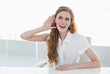 Young businesswoman with hand to her ear in office