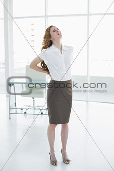 Elegant businesswoman suffering from back ache in office