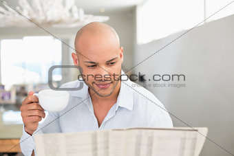 Man having coffee while reading newspaper at home