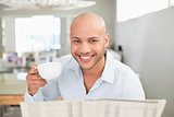 Smiling man with coffee cup reading newspaper at home