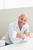 Smiling man holding coffee cup at home