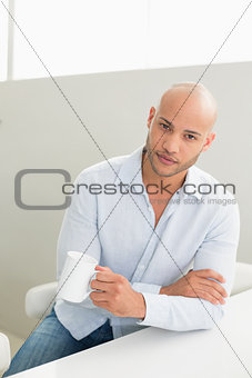 Serious man holding coffee cup at home