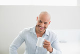 Smiling handsome man holding coffee cup at home