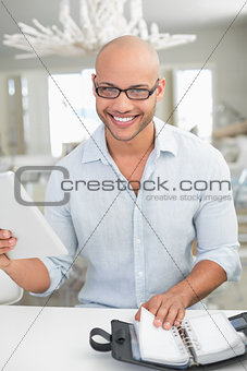 Casual smiling man with digital tablet and diary at home