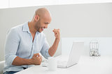 Smiling casual man using laptop at home