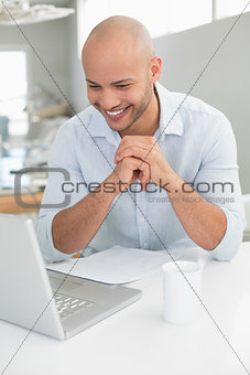 Casual smiling man using laptop at home