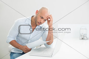 Worried casual young man using laptop at home