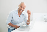 Portrait of smiling casual man with laptop at home