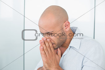 Sad casual man with hands to his face at home