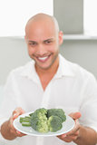 Smiling handsome man holding a plate of broccoli