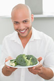 Smiling man holding a plate of broccoli