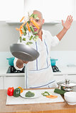 Man tossing vegetables in air at kitchen