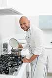 Side view of a smiling man preparing food in kitchen