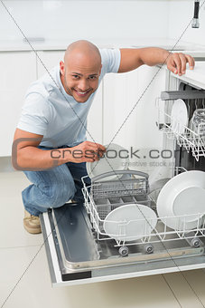 Portrait of a smiling man using dish washer in kitchen