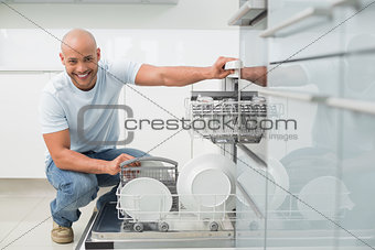 Portrait of smiling man using dish washer in kitchen