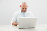 Casual smiling man using laptop at desk