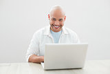 Portrait of casual smiling man using laptop at desk