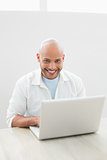 Portrait of a casual smiling man using laptop at desk