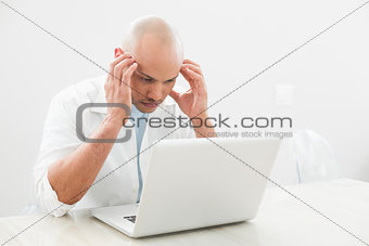 Concentrated worried casual man using laptop at desk